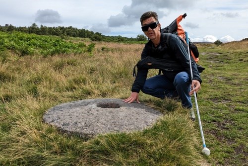 Michael next to a millstone on a walk in to the crag