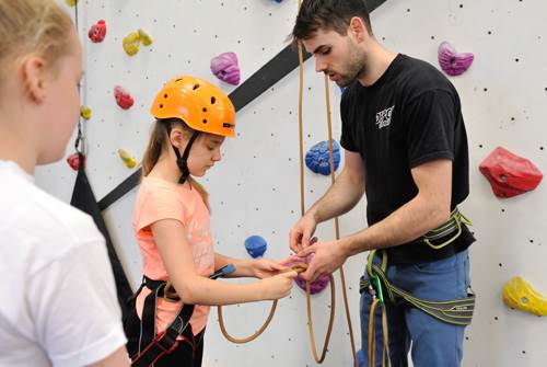 Man rethreading a figure of eight for young girl